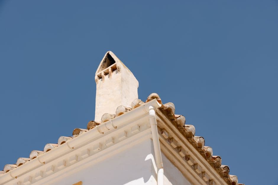 Operarios colocando teja cerámica curva sobre cubierta inclinada en una vivienda unifamiliar española