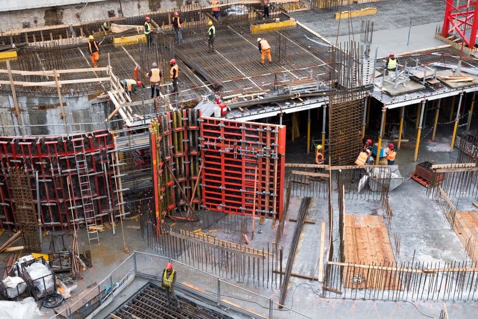 Trabajadores montando encofrado metálico para forjado de hormigón en obra de edificación