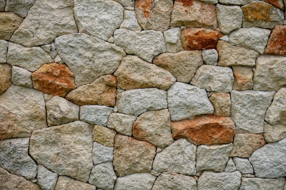 Oficial colocando chapado de piedra natural en una fachada exterior, con losas de pizarra y mortero de agarre