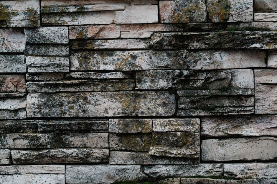 Fachada de casa rural revestida con piedra natural de cantera, acabado rústico en tonos grises y ocres