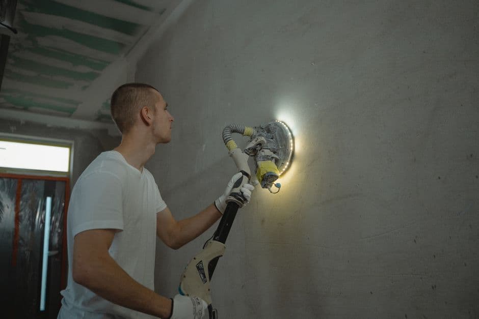 Operario aplicando pintura blanca con rodillo sobre una pared de pladur en un interior en reforma