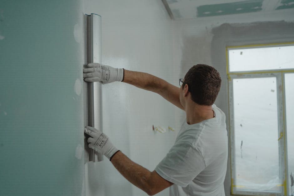 Oficial aplicando yeso proyectado sobre pared de ladrillo en una reforma de interior