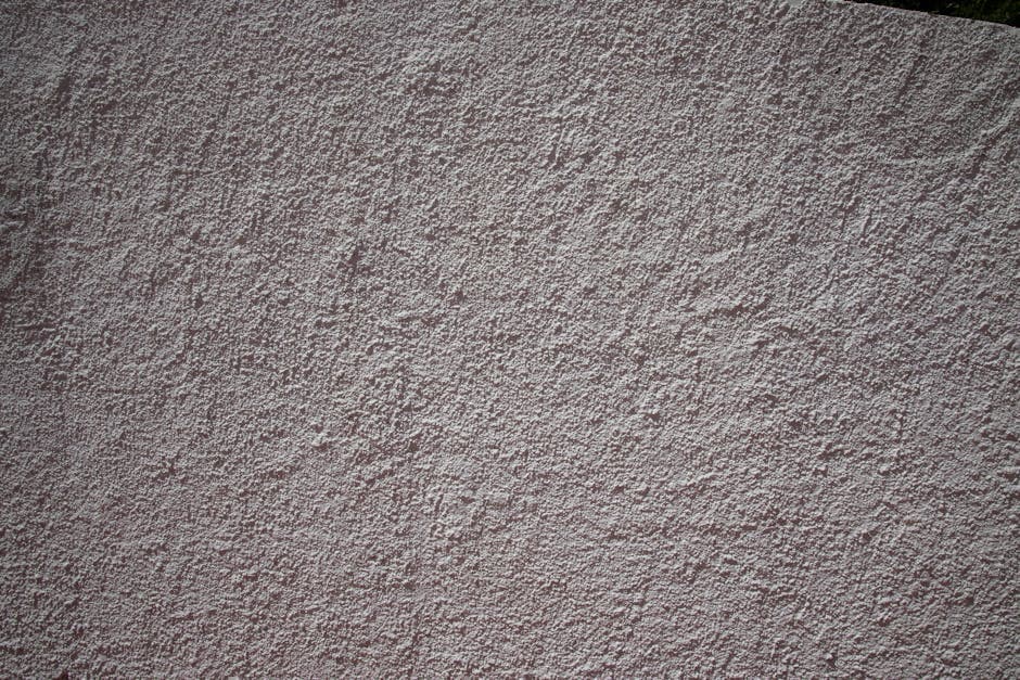 Operario aplicando graniplast con llana sobre fachada exterior texturada