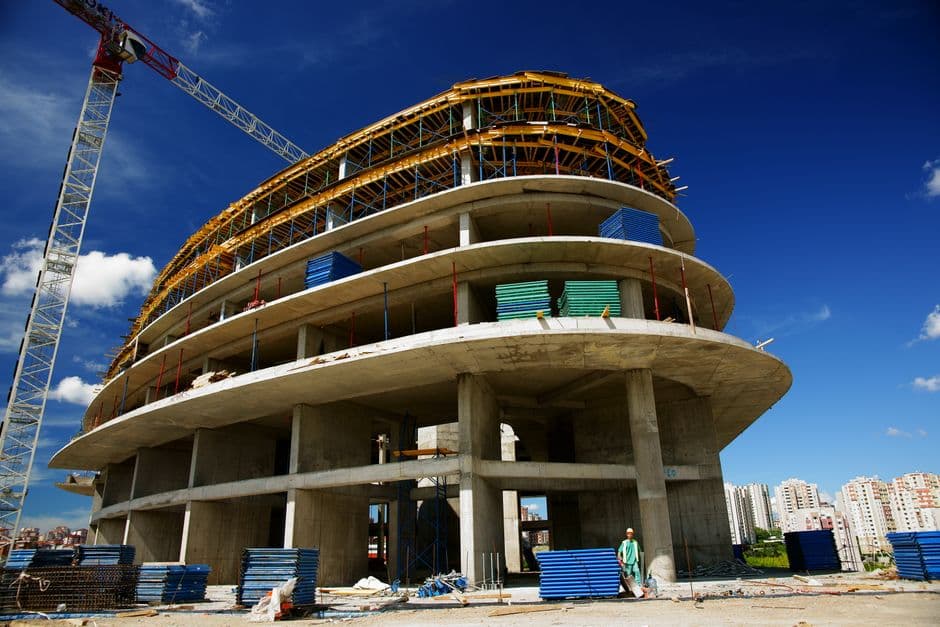 Grúa colocando una placa alveolar de hormigón prefabricado sobre una estructura de forjado en obra