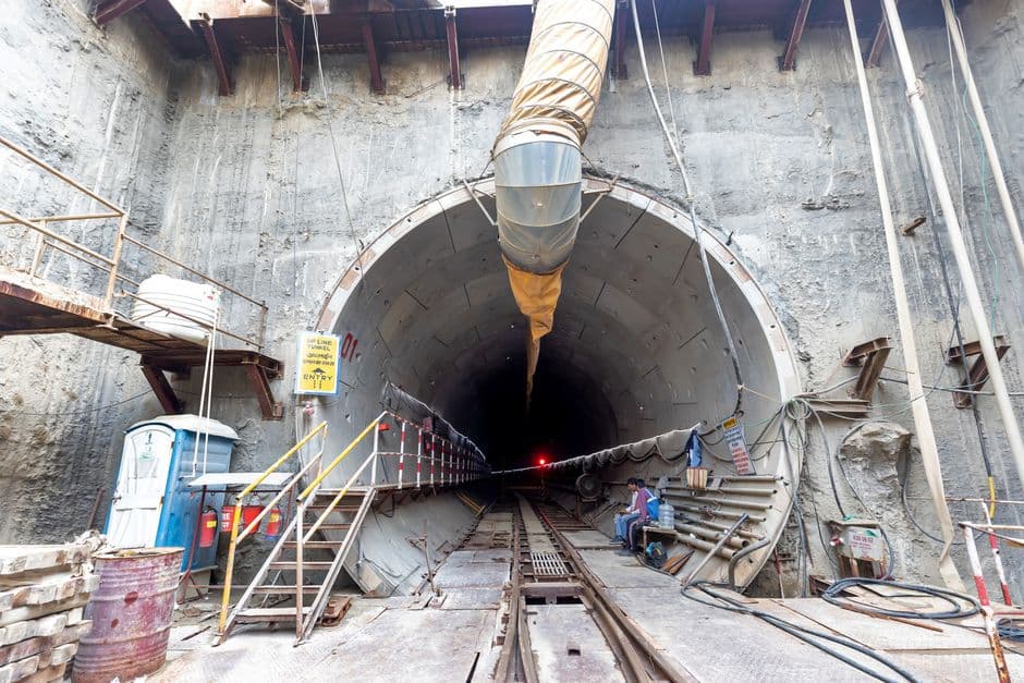 Operario proyectando hormigón gunitado con manguera sobre superficie rocosa en obra de contención