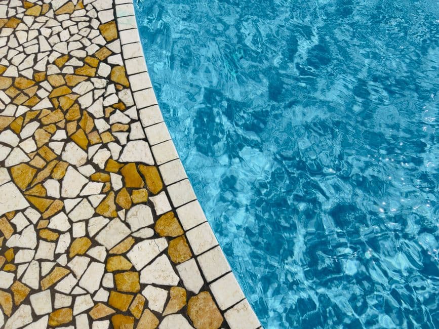 Operario aplicando lechada de rejuntado sobre gresite de mosaico en una piscina