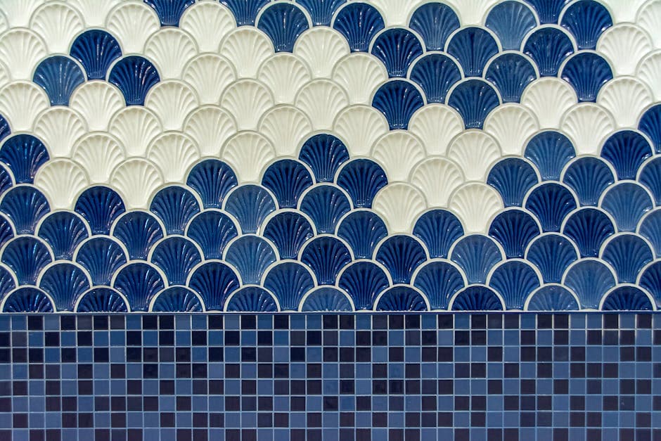 Operario colocando azulejos cerámicos en la pared de un baño con espátula y nivel