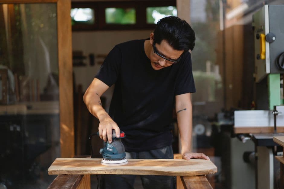 Operario profesional lijando y puliendo un suelo de parquet de madera con máquina industrial