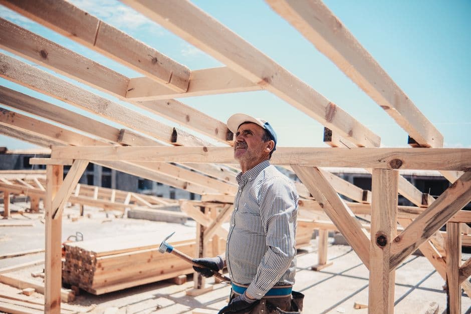 Operarios montando una estructura de madera para cubierta inclinada en obra nueva